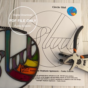 May include: A digital download PDF file for a stained glass pattern of the word "Slut" in a circle. The pattern is in black and white and includes a small circle with the word "Slut" in rainbow colors. The image also shows a finished stained glass piece and tools for making stained glass.