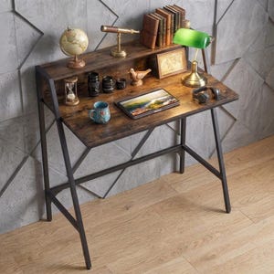 May include: A dark wood desk with a black metal frame featuring a top shelf holding a globe, a brass telescope, and a row of books. The desk surface contains a green lamp, a framed picture, a tablet, a blue mug, a wooden bird, and headphones.