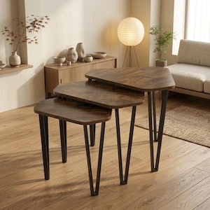 May include: A set of three nesting tables featuring dark brown wood-grain tops with rounded triangular shapes and black metal hairpin legs. The tables are arranged in a cascading formation, showcasing their varying heights and matching design.