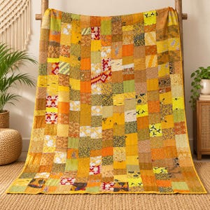 Op de afbeelding: Een rechthoekige patchwork quilt met een verscheidenheid aan stoffen vierkanten in tinten geel, oranje, olijfgroen en bruin. De quilt toont diverse patronen, waaronder bloemmotieven, geometrische en abstracte prints, allemaal verbonden met zichtbare doorstiksteken.