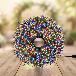 May include: A circular coil of multi-colored LED string lights featuring small, vibrant bulbs in red, green, blue, yellow, and orange hues. The lights are wound tightly around a central opening and include a black electrical plug at the end.