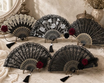 Puede incluir: Cinco abanicos plegables decorativos con encaje negro, marcos dorados intrincados y detalles de rosas de tela. Cada abanico muestra patrones únicos que incluyen bordados florales, bordes festoneados y borlas colgantes en las empuñaduras.