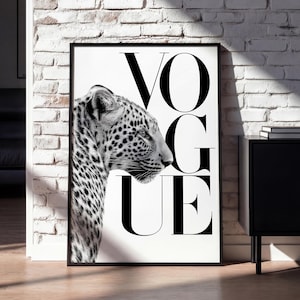 May include: A rectangular wall art print in a black frame featuring a black and white photograph of a leopard in profile on the left side and the word VOGUE printed in large, bold, black capital letters on the right side against a white background.