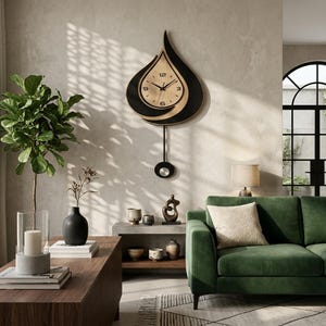 May include: A teardrop-shaped wall clock featuring a light wood face with black numerals at 3, 6, 9, and 12 o'clock. The clock is framed by a black curved border and includes a long pendulum with a circular weight hanging from the bottom centre.