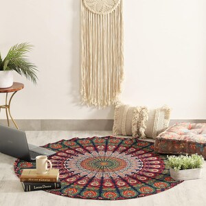 Peut inclure: Une tapisserie ronde présentant un motif mandala détaillé dans des tons de rouge profond, vert et or. Le tissu circulaire affiche des motifs floraux et géométriques complexes rayonnant depuis le centre, créant un design symétrique sur fond sombre.