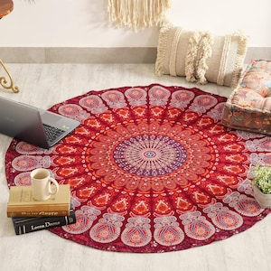 Peut inclure: Une tapisserie en tissu ronde présentant un motif mandala détaillé en rouge, orange et bleu avec des motifs géométriques et floraux complexes. Le textile circulaire est posé à plat, révélant un design symétrique rayonnant depuis un point central.