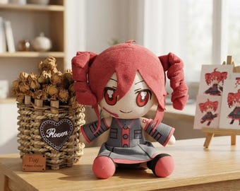 May include: A plush doll with red hair styled in two side ponytails, large red eyes, and a small smile. The doll wears a grey dress with red accents and buttons. It has a light skin tone and is seated upright, featuring a soft fabric construction.