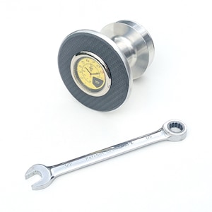 May include: A silver and black wrench with a yellow and black clock face attached to a silver base. The wrench is labeled "Ratchet Spanner 1/2".