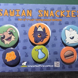 Könnte beinhalten: Ein Set aus sechs runden Ansteckbuttons auf einer blauen Karte mit der Aufschrift SAWIAN SNACKIES Set of 1-1.25 Handpressed Buttons. Die Buttons zeigen Illustrationen von Comic-Kreaturen, einer Birne und einem Hamburger.