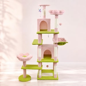 May include: A multi-level cat tree featuring pink and green carpeted platforms, two enclosed cubbies with arched openings, a flower-shaped top perch, a hanging butterfly toy, a suspended ball toy, and several sisal-wrapped scratching posts.