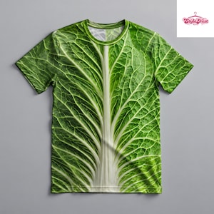 Könnte beinhalten: Ein kurzärmeliges T-Shirt mit Rundhalsausschnitt und einem hochauflösenden Ganzkörperdruck eines grünen Kohlblatts. Das Design zeigt eine markante, dicke weiße Mittelrippe, die in ein komplexes, strukturiertes Blattmuster übergeht.