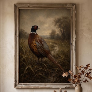 May include: A framed wall art print featuring a detailed painting of a male pheasant standing in a grassy field with a muted, overcast landscape background. The artwork is enclosed in a weathered, light-toned wooden frame with visible texture.