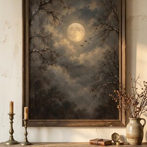 Op de afbeelding: Een ingelijste muurkunstprint met een volle maan die schijnt in een donkere, bewolkte nachtelijke hemel boven een bos van kale bomen met een paar vogels in de lucht. Het kunstwerk wordt gepresenteerd in een donkere houten lijst.