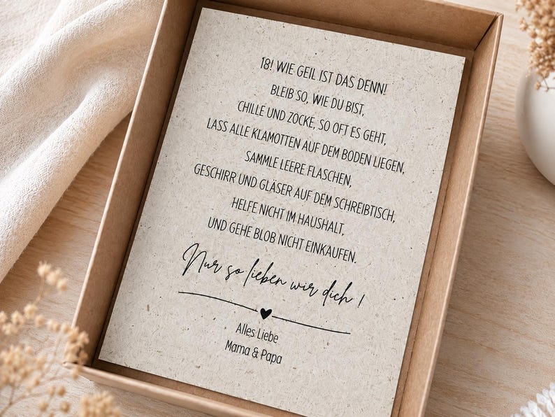 May include: A rectangular greeting card with a speckled, light beige paper texture inside a brown cardboard box. The card features black printed German text that reads: 18! WIE GEIL IST DAS DENN! BLEIB SO, WIE DU BIST, CHILLE UND ZOCKE, SO OFT ES GEHT, LASS ALLE KLAMOTTEN AUF DEM BODEN LIEGEN, SAMMLE LEERE FLASCHEN, GESCHIRR UND GL&Auml;SER AUF DEM SCHREIBTISCH, HELFE NICHT IM HAUSHALT, UND GEHE BLOB NICHT EINKAUFEN. Nur so lieben wir dich! ALLES LIEBE MAMA & PAPA.