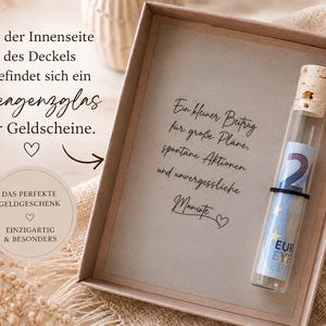 May include: A rectangular cardboard gift box containing a glass test tube with a cork stopper. Inside the tube is a rolled-up Euro banknote. The box features German text printed on the inner lid and a central card with German script text.