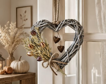 May include: A heart-shaped wreath made of grey woven willow branches, featuring a decorative bundle of dried wheat stalks and small dark purple tulip buds. A jute rope loop hangs the wreath, and two small brown metal hearts dangle from the centre.