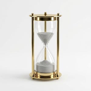 Puede incluir: Un reloj de arena de metal dorado con un bulbo de vidrio transparente lleno de arena gris fina. El marco consta de una base y una parte superior circulares conectadas por tres pilares verticales, con un pequeño pomo decorativo en el centro.