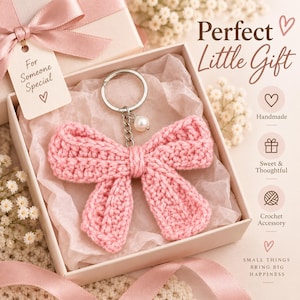 Può includere: Un portachiavi a forma di fiocco lavorato all'uncinetto in rosa chiaro con un anello in metallo argentato e un piccolo ciondolo a perla bianca, presentato in una scatola regalo quadrata con un nastro rosa e un'etichetta con la scritta For Someone Special.