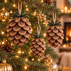 Puede incluir: Tres adornos de piña de crochet colgados en un árbol de Navidad. Cada adorno presenta escamas marrones texturizadas, una parte superior verde oscuro y pequeñas cuentas doradas, suspendido por un lazo de cuerda de color canela.