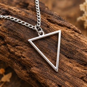 May include: A silver-toned necklace featuring a hollow, equilateral triangle pendant suspended from a matching metal curb chain. The pendant is a simple, open geometric frame with a polished finish, connected to the chain by a small jump ring.