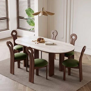 May include: An oval dining table with a light-coloured stone top and dark wood base, accompanied by six chairs featuring dark wood frames with circular cutouts at the top and round, olive green upholstered seats arranged around the table.