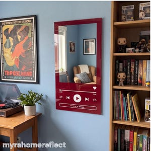 May include: A rectangular wall mirror featuring a deep red border with a white graphic overlay resembling a digital music player interface. The design includes playback controls, a progress bar, a heart icon, and the text "forever & always".