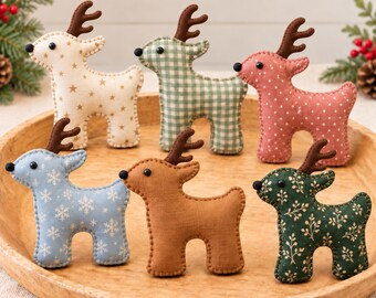 May include: Six plush reindeer ornaments featuring various fabric patterns including cream with gold stars, green gingham, pink with white dots, light blue with white snowflakes, solid tan, and dark green with a white botanical print, all with brown antlers.