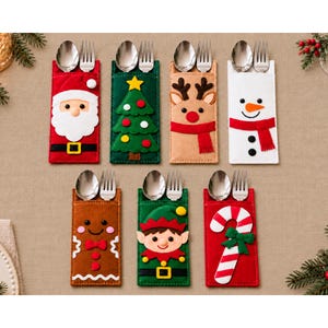May include: Seven felt cutlery holders featuring Christmas designs including Santa Claus, a green tree, a reindeer, a snowman, a gingerbread person, an elf, and a candy cane. Each rectangular sleeve holds a silver metal spoon and fork.