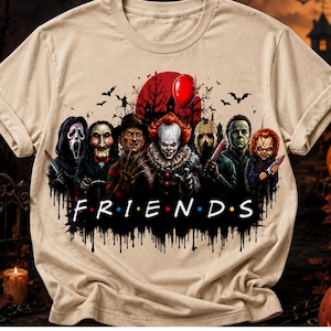 Può includere: Una t-shirt beige con una stampa grafica di sette personaggi di film horror in piedi sotto una luna rossa e un singolo palloncino rosso. Il testo "F R I E N D S" è stampato in bianco con punti colorati tra le lettere sotto i personaggi.