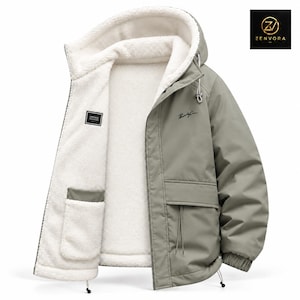 Peut inclure: Une veste à capuche vert sauge avec une doublure en polaire sherpa blanche. La veste présente une fermeture éclair frontale, des manches longues avec poignets élastiques et deux grandes poches. Une étiquette noire indique VINTAGE FASHION.