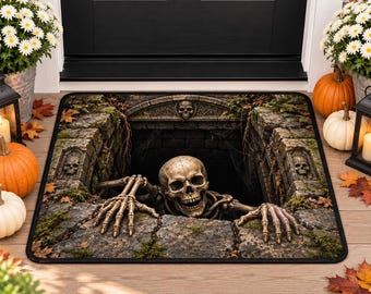 Puede incluir: Un felpudo rectangular con un gráfico en estilo 3D de un esqueleto humano saliendo de un foso oscuro con paredes de piedra. El diseño incluye texturas de piedra con musgo, pequeñas calaveras talladas en las paredes y una abertura central.