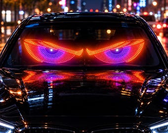 Puede incluir: Un parabrisas de coche negro presenta una gran pantalla LED iluminada que muestra dos ojos estilizados y brillantes. Los ojos tienen un borde exterior naranja brillante y un patrón interior de puntos morados y azules.