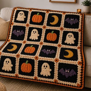 May include: A rectangular crochet blanket featuring a grid of black squares, each containing a different motif including cream-colored ghosts, orange pumpkins, yellow crescent moons, and purple bats, all bordered by orange and cream yarn.