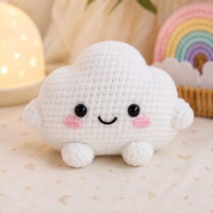 Puede incluir: Un juguete de peluche de nube tejido a ganchillo en color blanco con forma redondeada y esponjosa, dos brazos pequeños y dos pies pequeños. La nube tiene dos ojos de seguridad de plástico negro, una sonrisa negra bordada y mejillas rosadas.