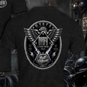 May include: A black t-shirt featuring a large circular graphic on the back. The design includes a winged eagle emblem, two handguns, and text that reads MYOFB CLOTHING COMPANY 2026, ALL GAS NO BRAKES, and Built Different, Respect, Honesty, Loyalty.
