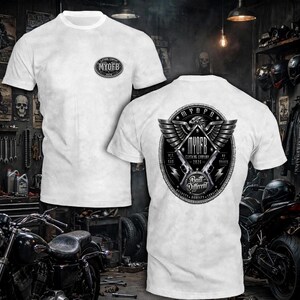 May include: A white short-sleeve t-shirt featuring a small oval logo on the left chest that reads MYOFB 2026. The back displays a large circular graphic with an eagle, two pistols, and the text MYOFB CLOTHING COMPANY 2026 BUILT DIFFERENT.