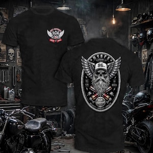 May include: A black t-shirt featuring a small graphic on the front chest with wings and the text Built Different 2024. The back displays a large graphic of a bearded skull wearing a cap with the number 86, wings, and the text My Ofb Clothing Co.