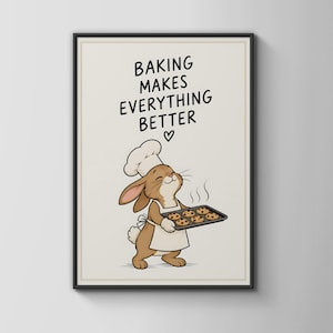 Op de afbeelding: Een ingelijste kunstprint met een bruin cartoonkonijn dat een witte koksmuts en schort draagt en een bakplaat met zes chocoladekoekjes vasthoudt. De tekst erboven luidt BAKING MAKES EVERYTHING BETTER met een klein hartje eronder.