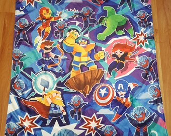 May include: A blue, purple, and teal blanket featuring cartoon illustrations of various superheroes and villains. The design includes Iron Man, Hulk, Black Widow, Captain America, Thor, and Thanos, along with Ultron characters and starburst accents.