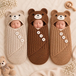 Può includere: Tre neonati avvolti in fasce all'uncinetto a forma di orso nei toni del beige, marrone scuro e marrone chiaro. Ogni fascia presenta un cappuccio con orecchie da orso, un muso bianco con naso e bocca ricamati e tre bottoni bianchi sul davanti.