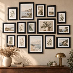 May include: A gallery wall arrangement featuring fourteen black-framed prints with neutral-toned botanical, coastal, and abstract art. Below the frames sits a wooden console table with a beige ceramic vase, a small bowl, and a brass lamp.