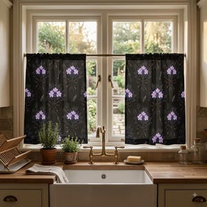 Puede incluir: Un par de cortinas de cocina negras con un patrón repetitivo de ramos de flores moradas atados con cintas y pequeñas llaves. Las cortinas cuelgan de una fina barra de metal sobre un fregadero, mostrando una tela oscura con motivos.
