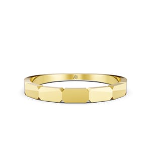 May include: A polished yellow gold ring featuring a series of connected, flat-faced geometric segments around the band. The interior of the ring displays a small, engraved logo consisting of the letters AD in a stylized, cursive script font.
