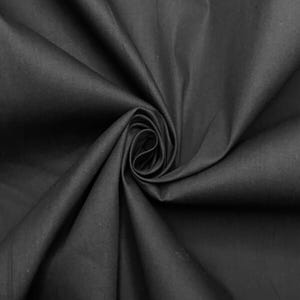 Puede incluir: Una tela negra sólida con una textura suave y mate, dispuesta en un pliegue en espiral central que crea sombras y reflejos profundos y fluidos en la superficie, enfatizando la caída y el tono oscuro consistente del material.