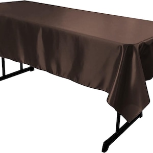 Peut inclure: Une table rectangulaire recouverte d'une nappe en satin marron foncé uni. Le tissu présente une finition lisse et réfléchissante et retombe sur les bords du cadre de table pliant noir, doté de pieds en métal fins et d'une barre de support.