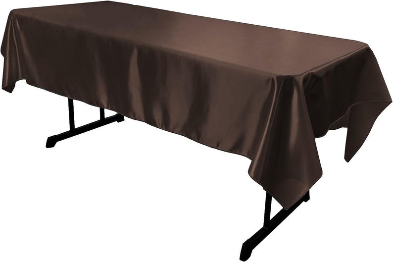 May include: A rectangular table covered with a solid dark brown satin tablecloth. The fabric has a smooth, reflective finish and drapes over the edges of the black folding table frame, which features thin metal legs and a horizontal support bar.
