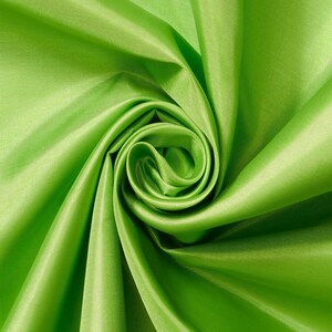 May include: A vibrant lime green fabric with a smooth, lustrous finish. The material is gathered into a central spiral, creating deep, flowing folds and shadows that highlight the reflective quality and consistent color of the textile surface.