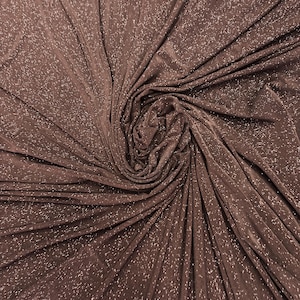 May include: A dark brown fabric featuring a dense, shimmering silver glitter finish throughout the material. The textile is gathered in a central spiral, creating deep, radiating folds and pleats that highlight the reflective metallic texture.