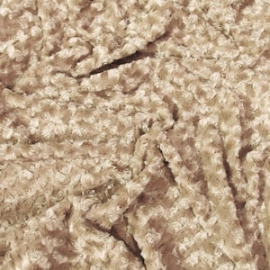 May include: A beige fabric featuring a dense, textured pile with a repeating circular, swirled pattern. The material has a soft, plush appearance with light and shadow creating depth across the surface of the folded, shaggy textile material.