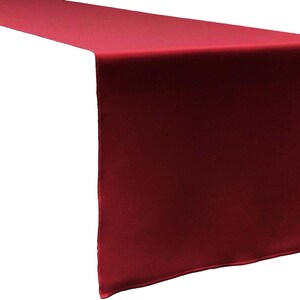 Peut inclure: Un chemin de table rouge foncé uni avec une texture de tissu lisse et mate. Le chemin présente des bords droits et nets ainsi qu'une forme rectangulaire, conçu pour retomber sur le côté d'une table avec une couleur uniforme et constante.